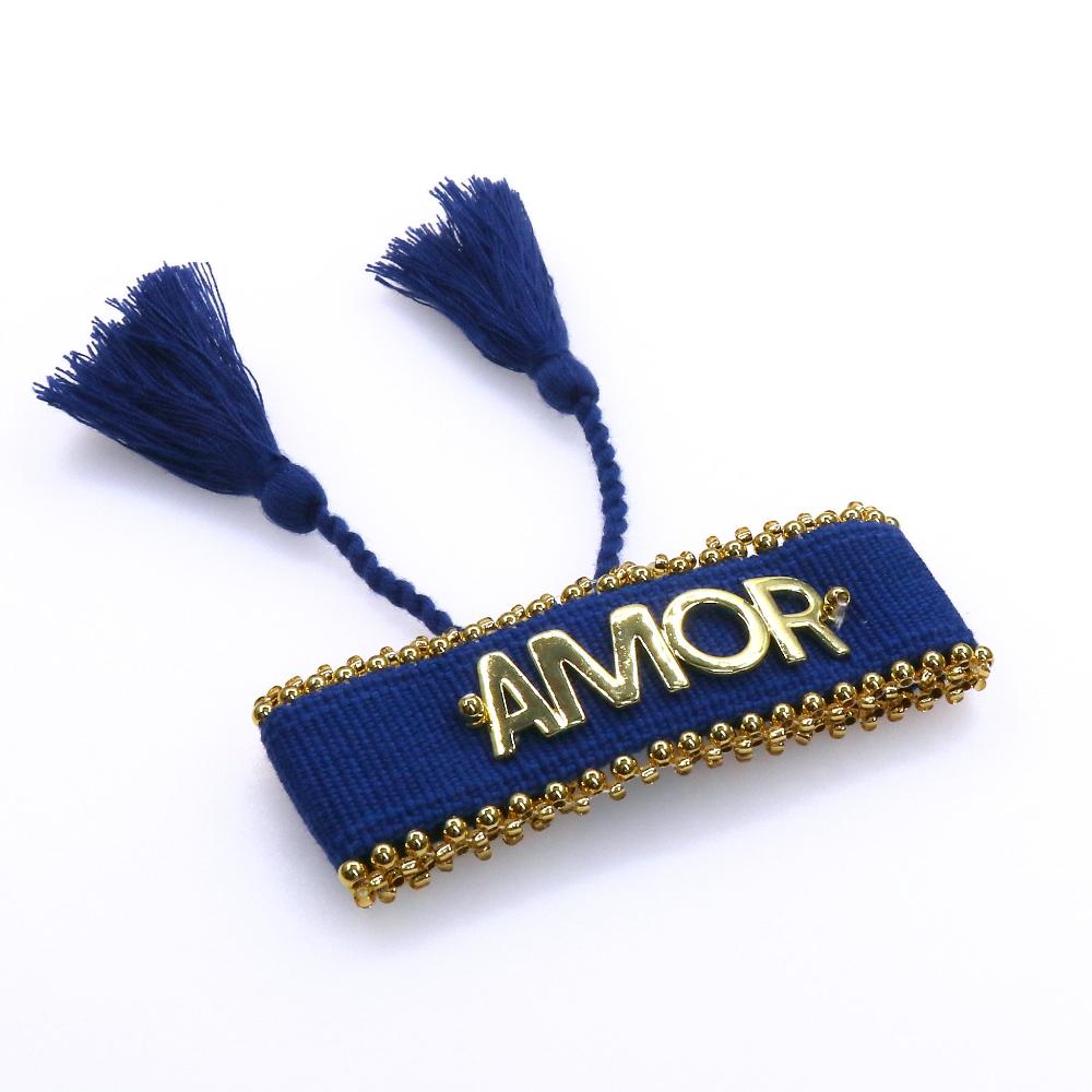 Blue fabric AMOR bracelet with gold lettering and decorative beads, handcrafted with tassels