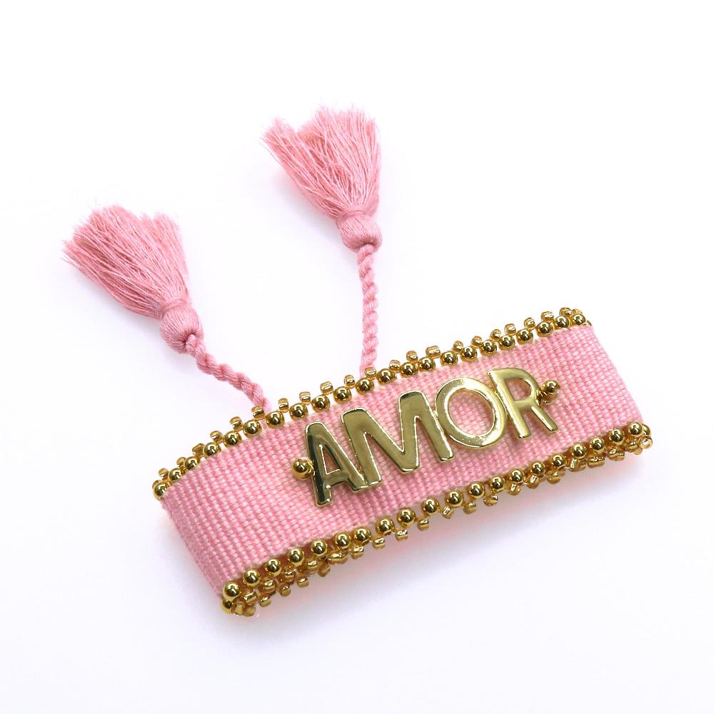 Pink handcrafted fabric AMOR bracelet with gold bead accents and tassels