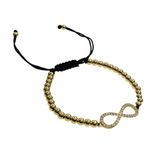 Gold beaded slider bracelet with diamond-encrusted infinity symbol and adjustable black cord