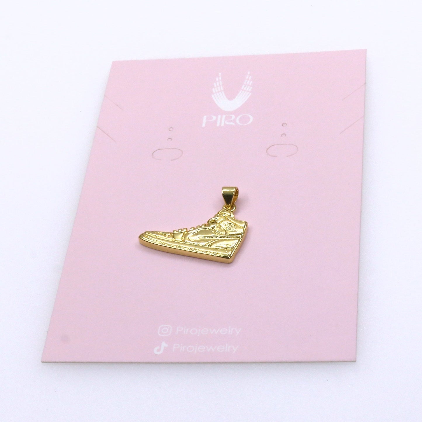 Gold-colored SHOE CHARM on pink display card for shoe accessory