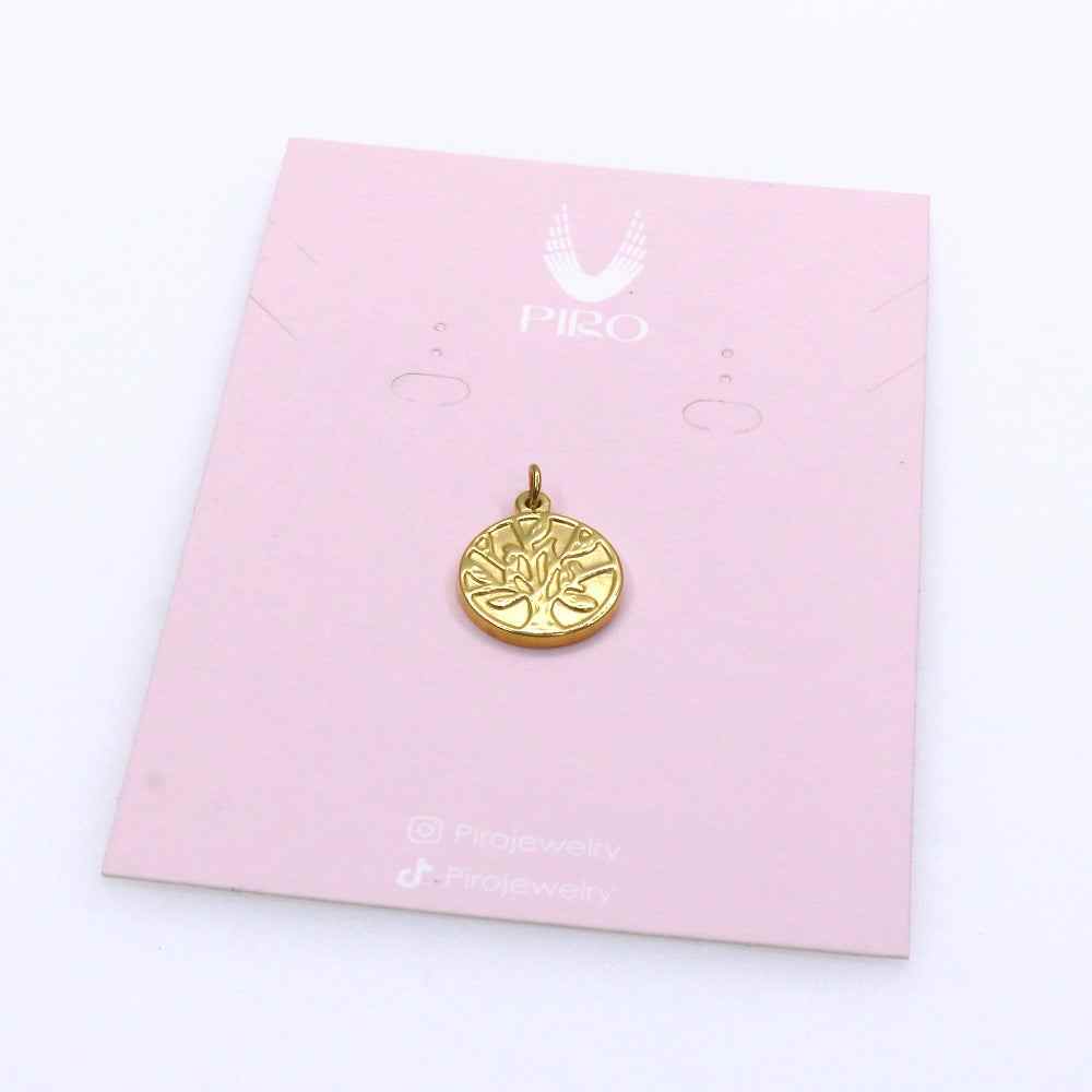 Gold Tree of Life charm on a pink card, symbolizing harmony and growth.