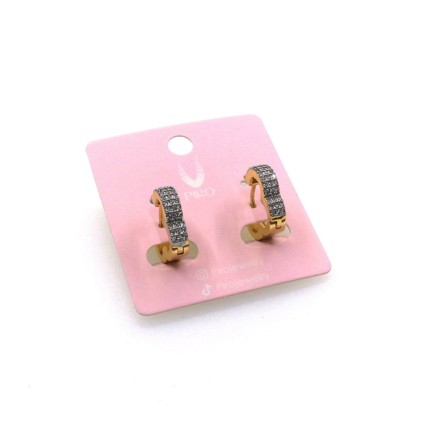Gold Trebol Baguette Huggie earrings with sparkling baguette-cut stones on a pink display card