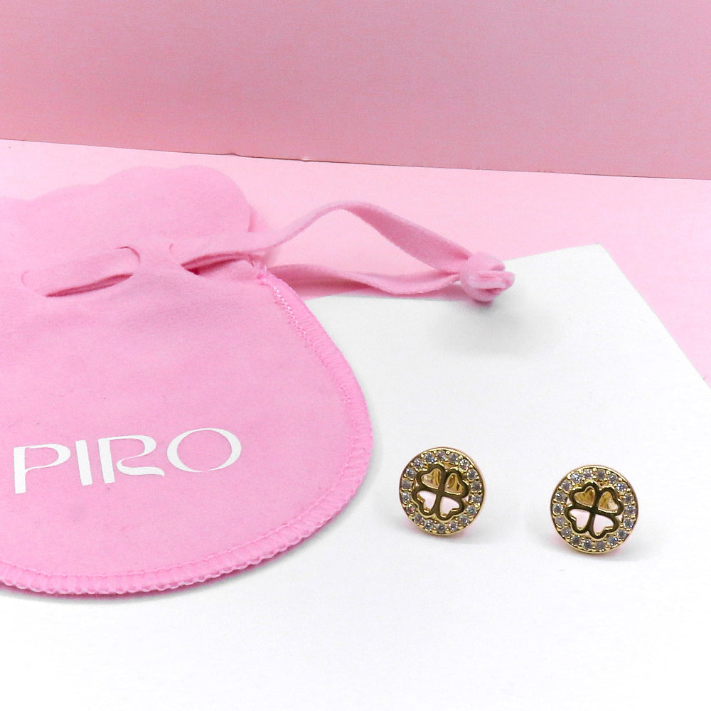 Gold circle clover stud earrings with rhinestone accents and pink drawstring pouch