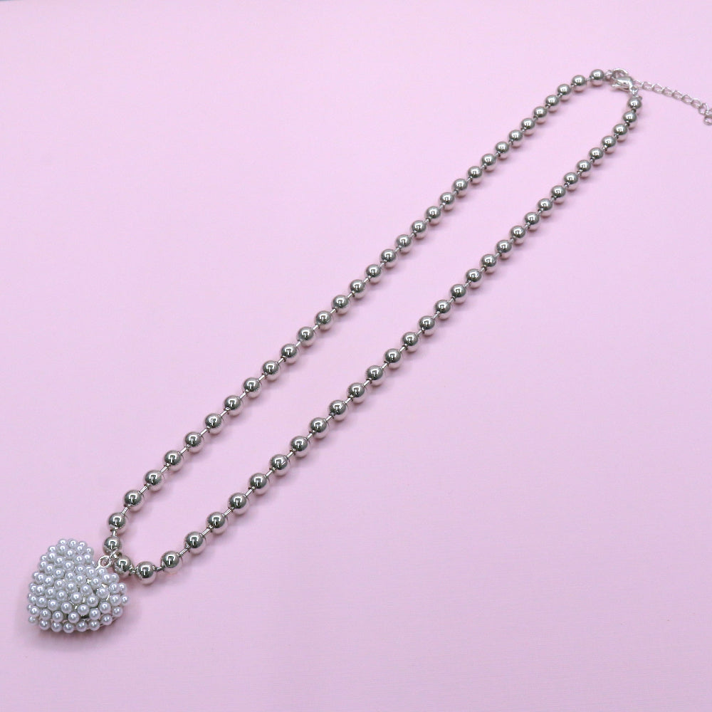 Stainless steel Love Pearl Chain necklace with a heart-shaped pearl pendant on a beaded chain against a pink background