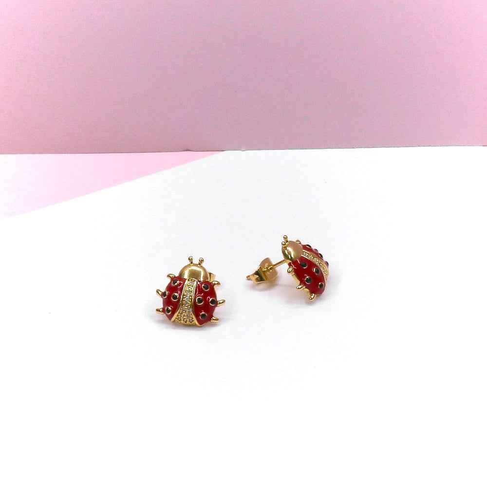 Ladybug stud earrings with intricate design on a pastel background.