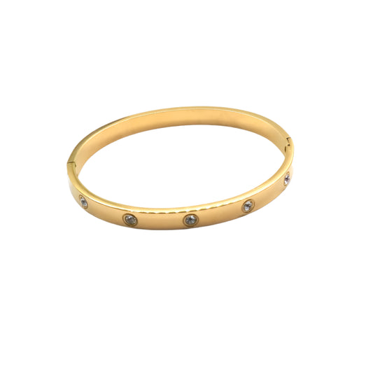 Gold bangle with embedded stones on a white background