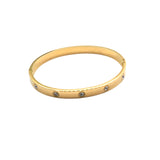 Gold bangle with embedded stones on a white background