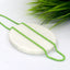 Green stainless steel candy chain laid on white marble display with green plant background