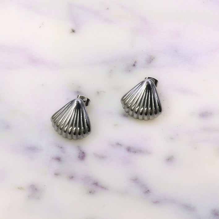 Silver stainless steel SEA-SHELL shaped stud earrings on white marble surface