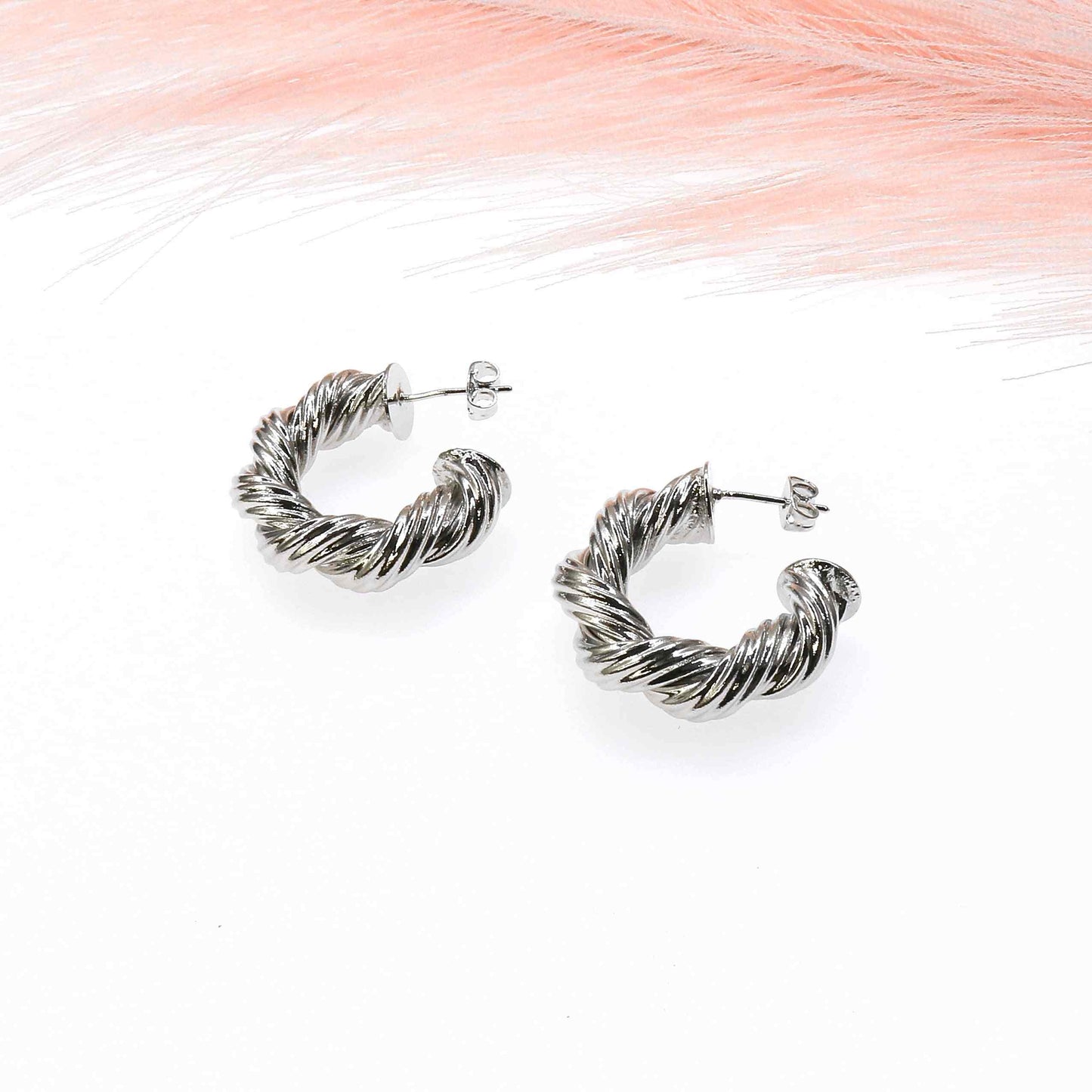 Twisted stainless steel TWISTED HOOP earrings with a sleek, elegant design on white background