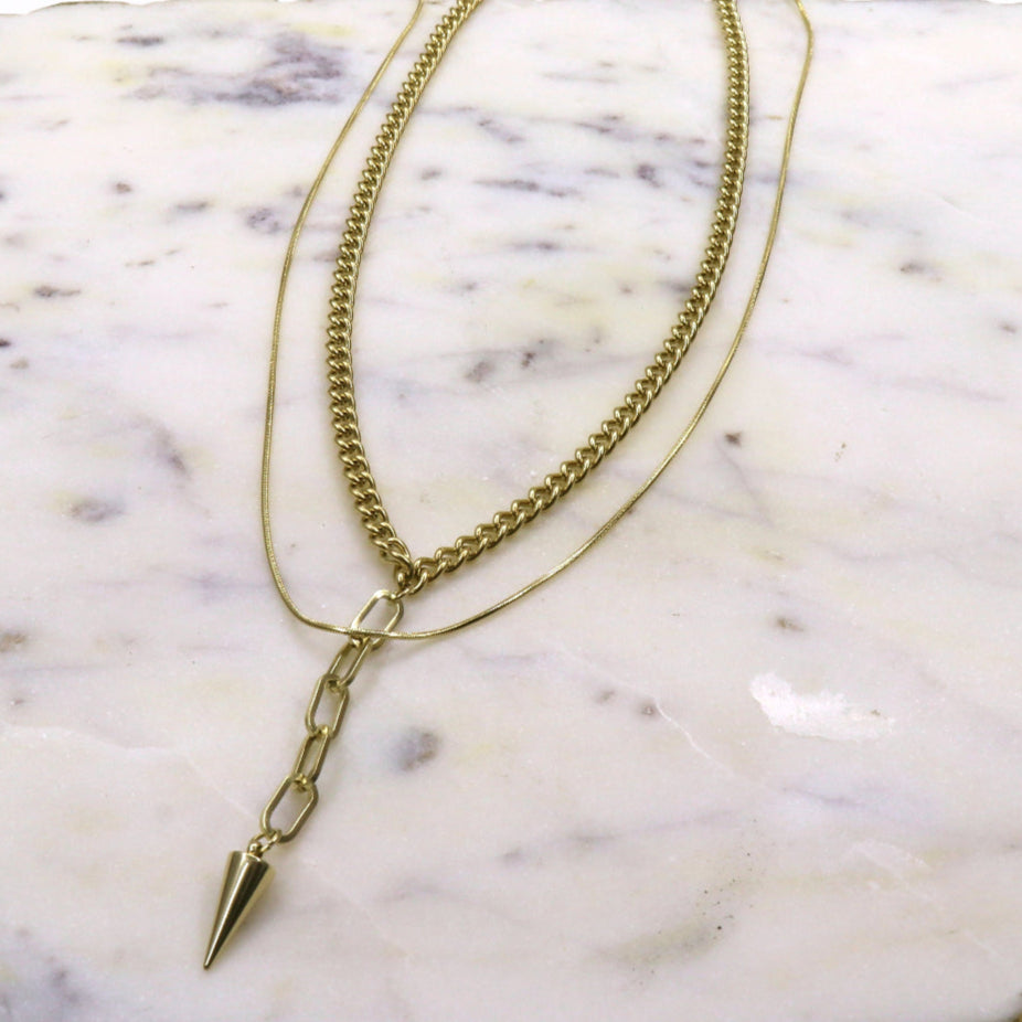 LAYERING CHAIN SPIKE CHARM necklace with spike charm pendant on marble surface