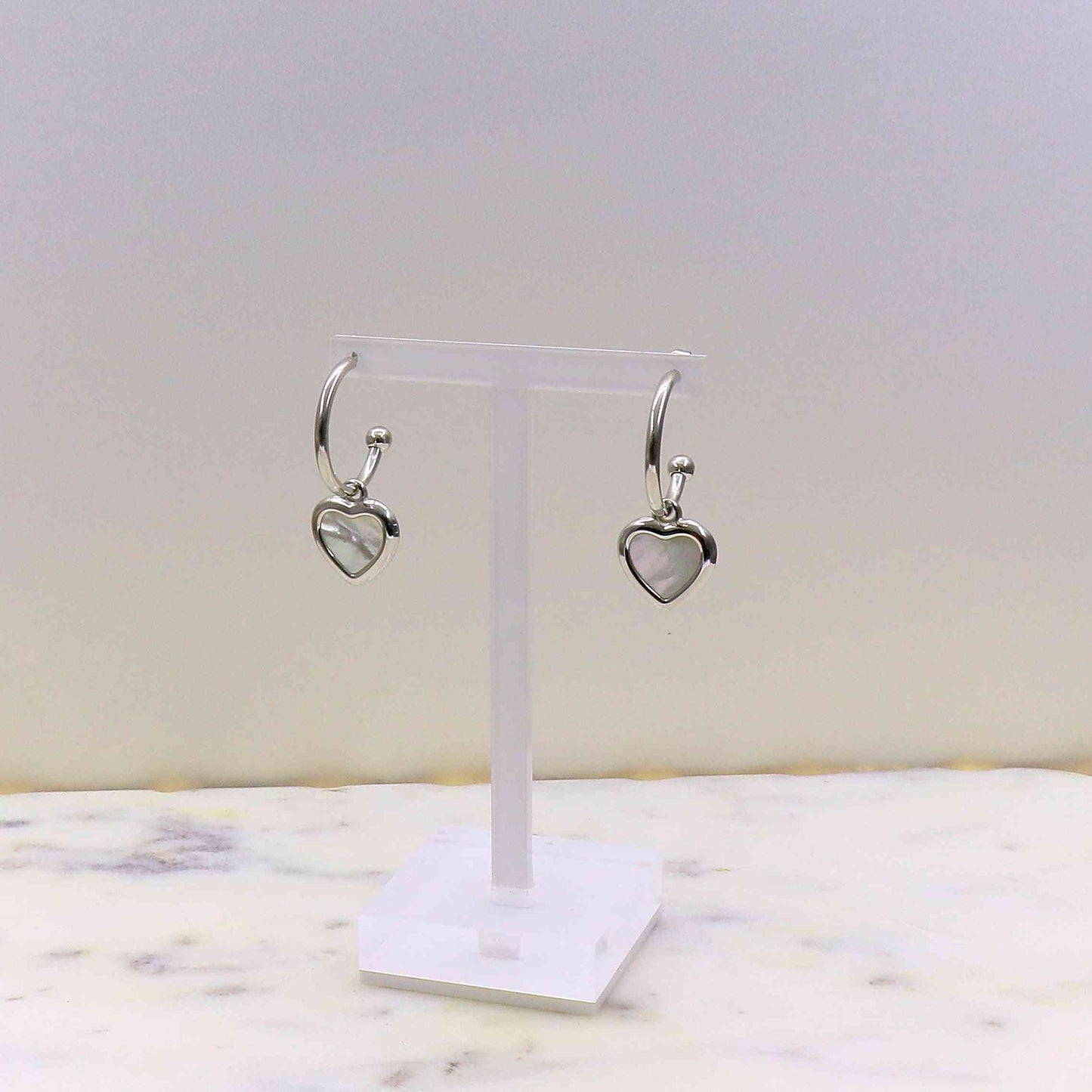 Elegant stainless steel romance earrings with heart-shaped love charm on display stand