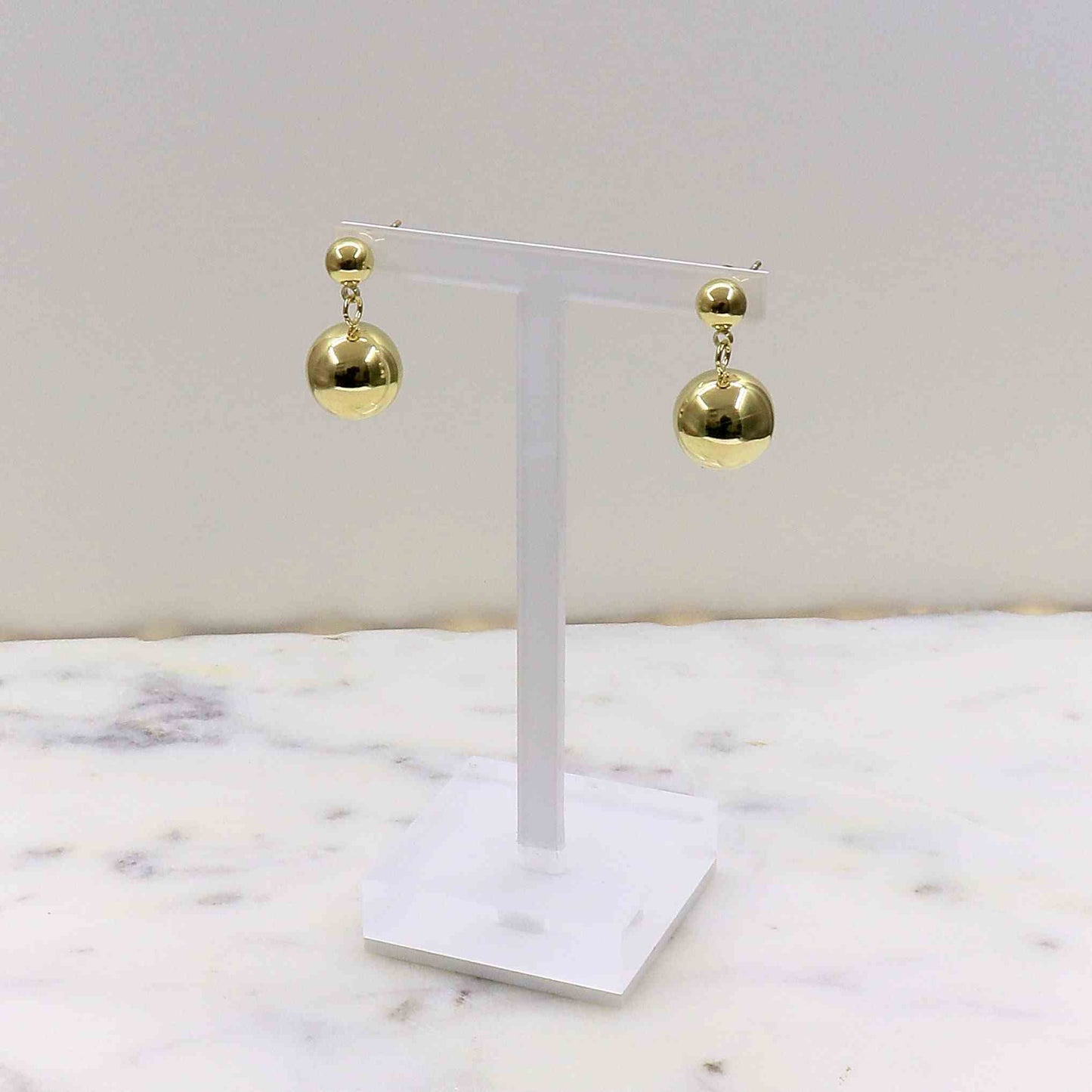 Gold stainless steel World Earring with spherical design on white display stand
