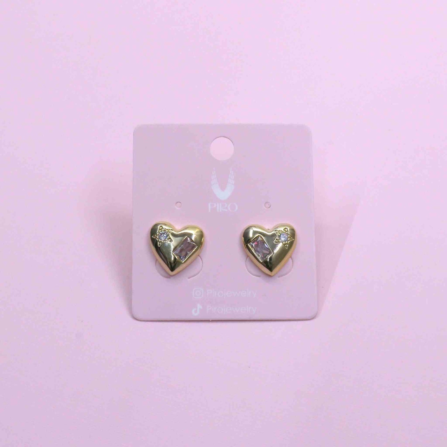 Gold zirconia heart-shaped stud earrings on a display card