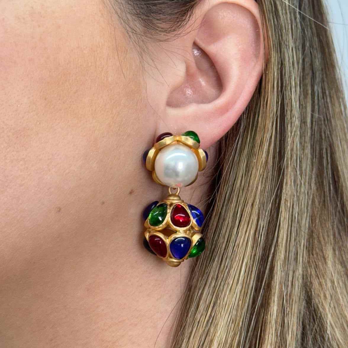 Close-up of a monarca earring with gold fill, a large pearl, and colorful gemstones on a woman's ear