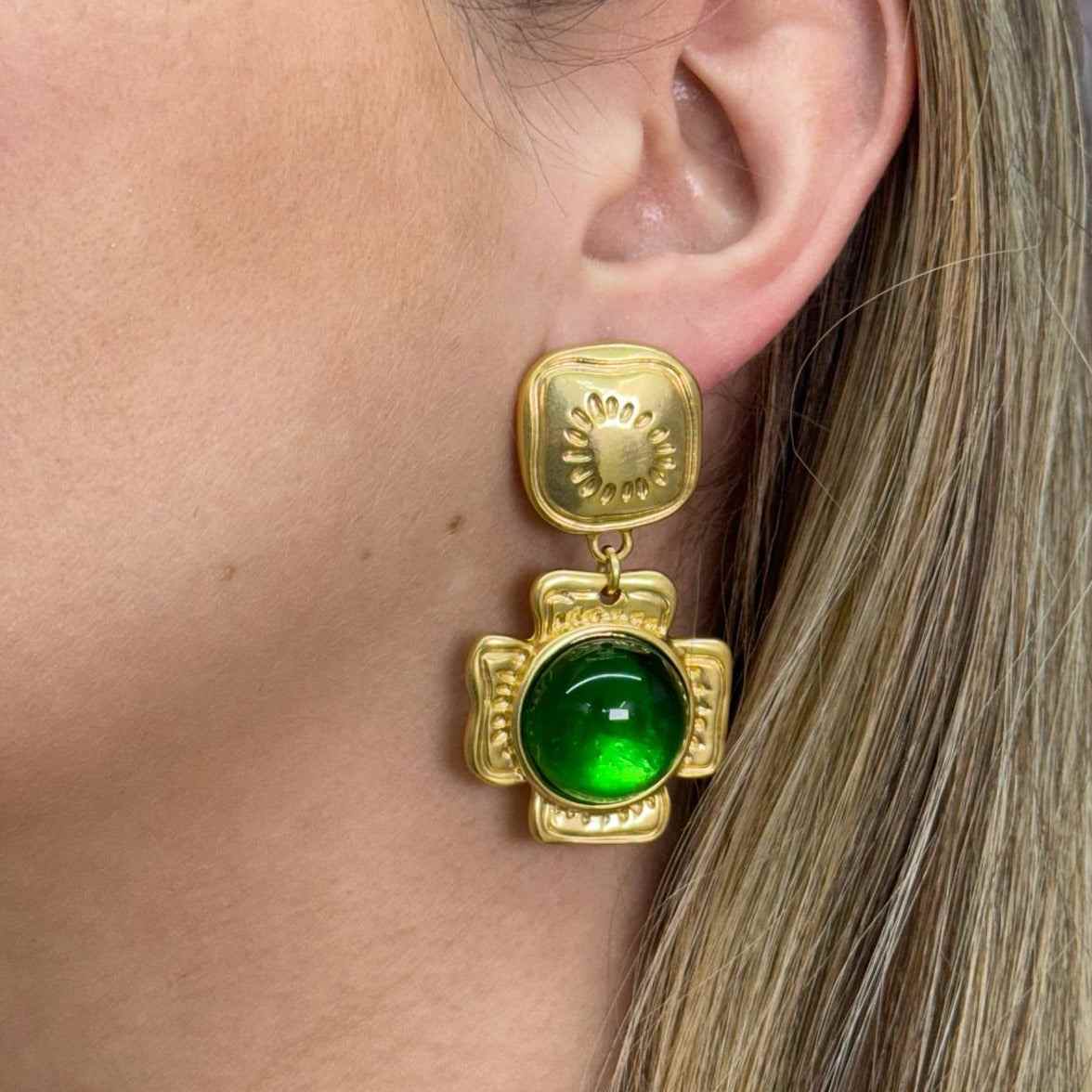 Close-up of a gold-filled DUQUESA earring with a green gemstone worn on the ear
