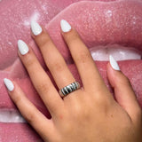 Steel ring worn on hand with white nail polish against pink lips background