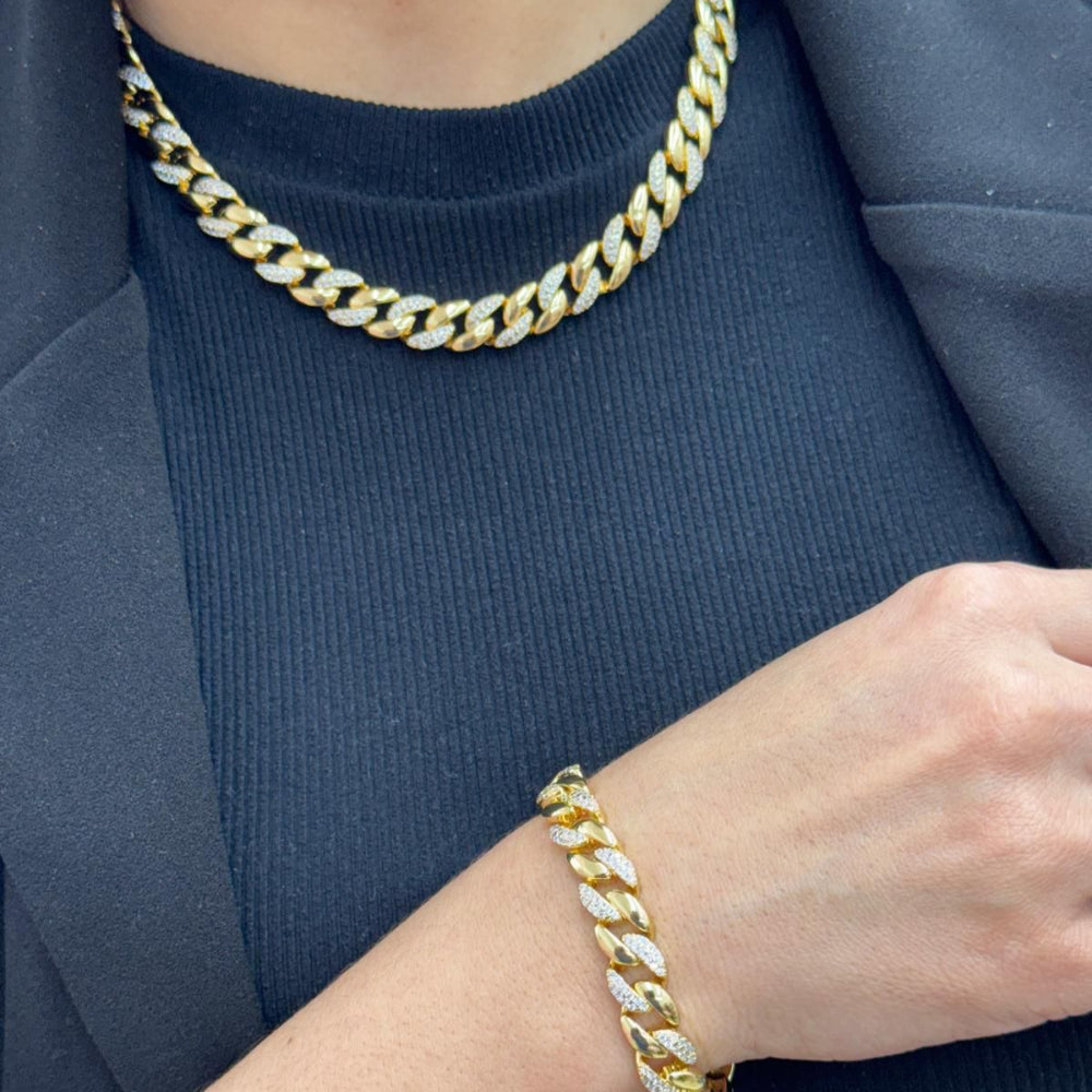 Gold chain necklace and bracelet on a person wearing a blue outfit