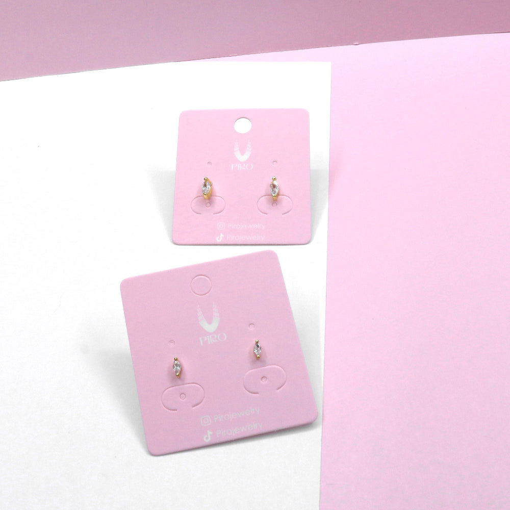 Pair of tiny oval zirconia stud earrings on pink display cards against a pink and white background