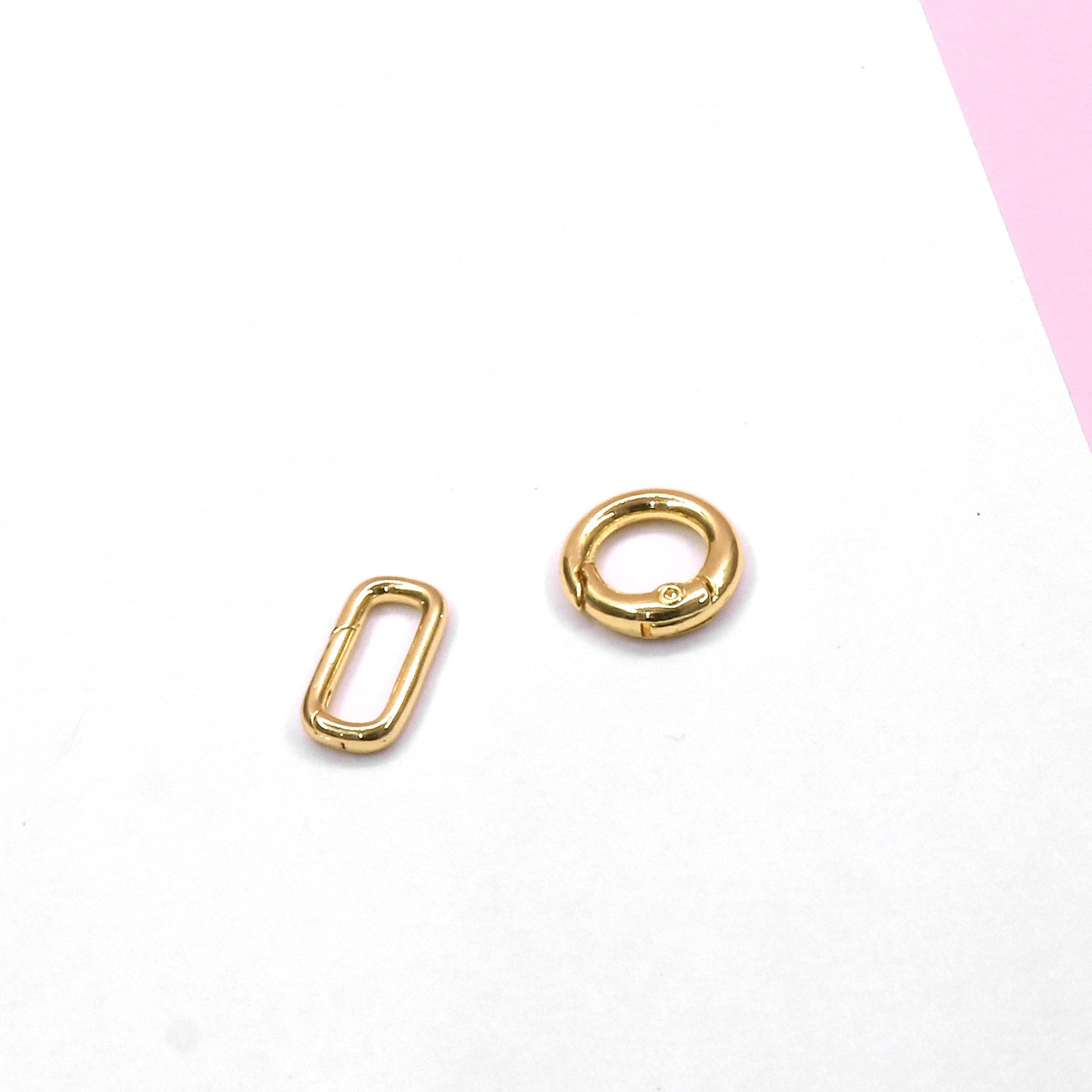 gold lock accessories parts including a round ring and a rectangular link on white and pink background