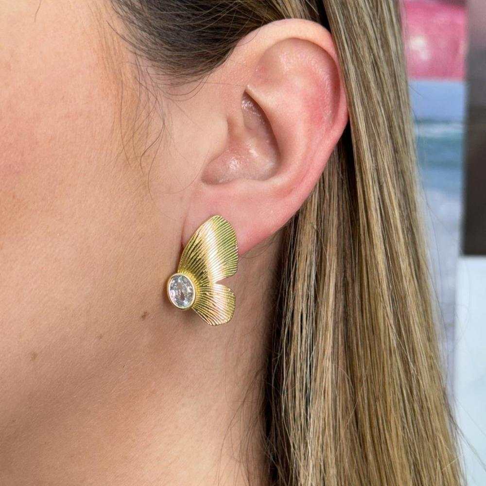 Woman wearing gold stainless steel butterfly wing design earring with clear gemstone stud