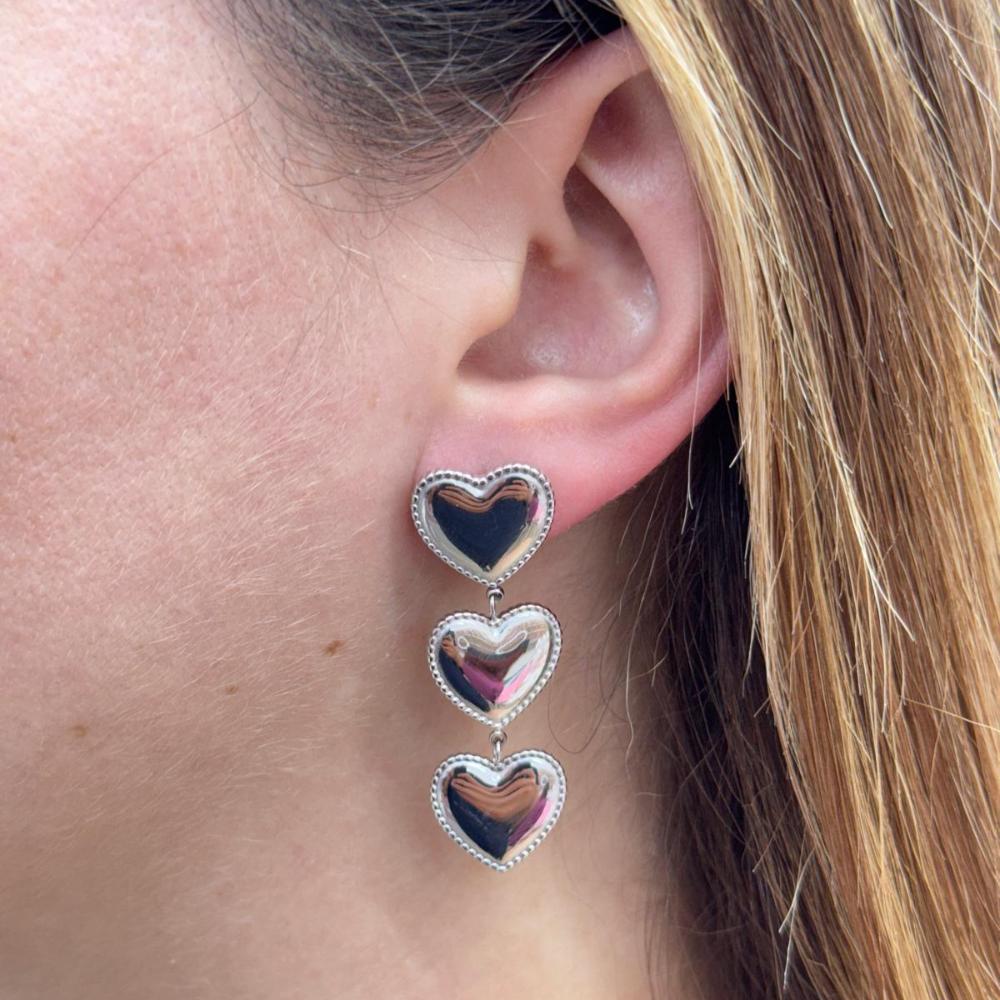 Three heart-shaped long silver 3 HEART LONG EARRING worn on ear with beaded edge design