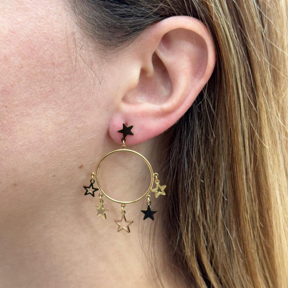 Close-up of a woman's ear wearing MINI STARS EARRING gold hoop with black and gold star charms