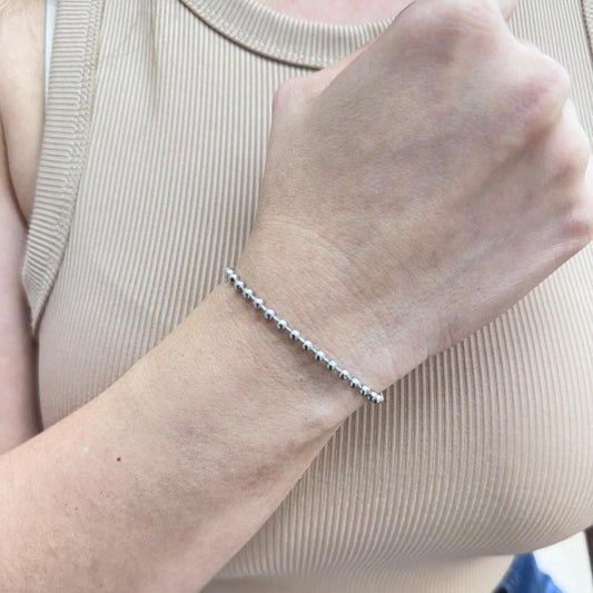 Silver tiny beads adjustable bracelet on wrist wearing beige top