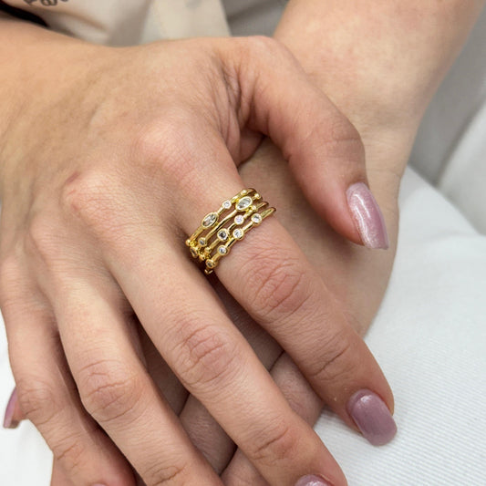 Close-up of a hand wearing a gold ring with pink nail polish on a blurred background
