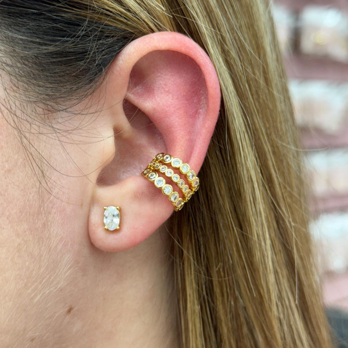 Close-up of a person's ear wearing gold hoop earrings with small pearls.
