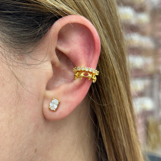 Close-up of an ear wearing gold hoop earrings with a blurred background