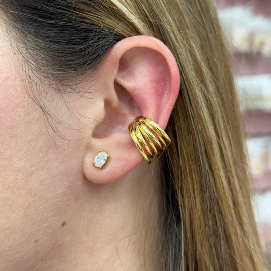 Close-up of a person wearing gold earrings with a blurred background