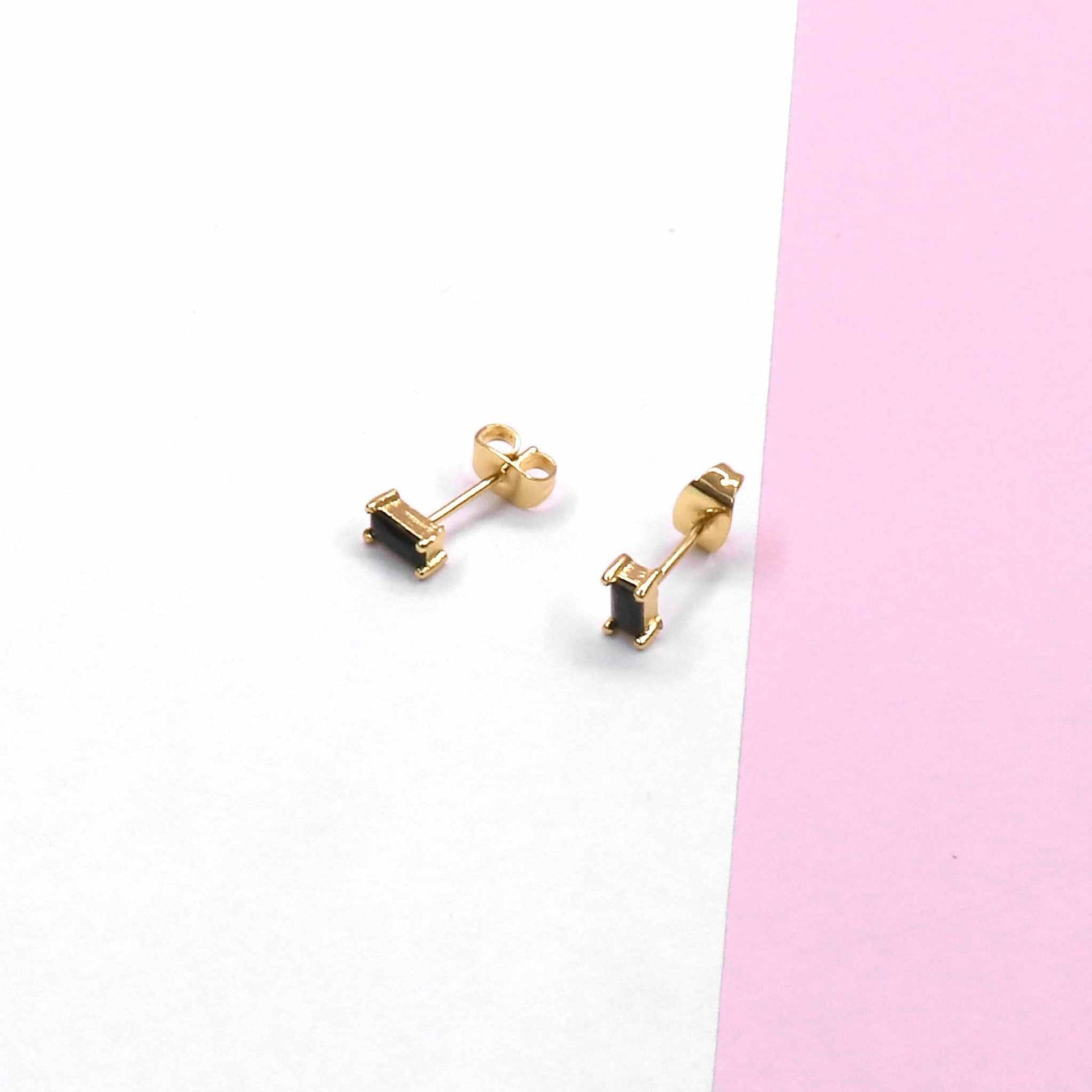 MINI SQUARE STUD earrings with modern design on pink and white background.