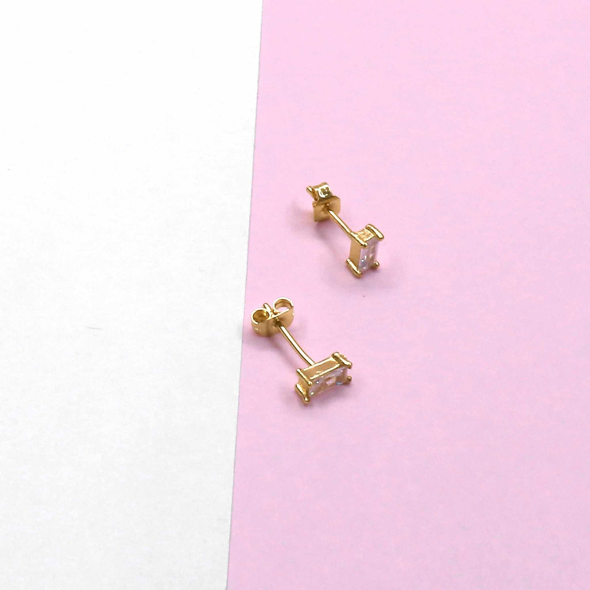MINI SQUARE STUD earrings on a pink and white background.