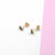 Mini square stud earrings on a white and pink surface, showcasing their elegant and modern design.
