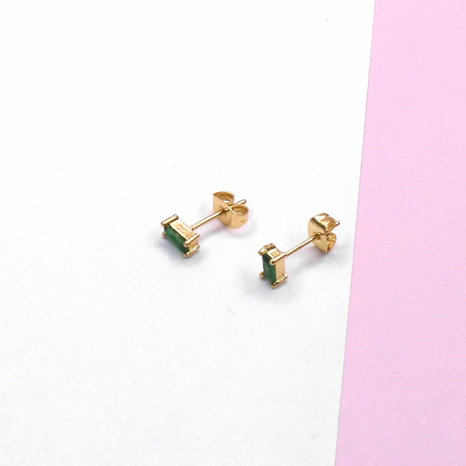 Mini square stud earrings on a white and pink surface, showcasing their elegant and modern design.