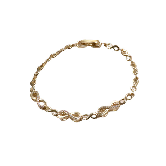 Gold bracelet with intricate designs on a light purple background