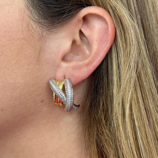Close-up of an ear wearing a stylish X chunky earring with intertwined gold and silver textured design