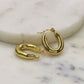 Gold oval earrings made from stainless steel on a marble surface.