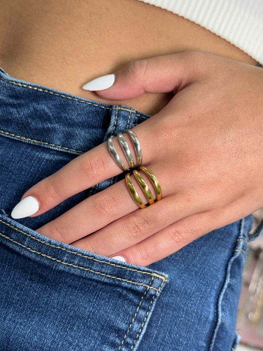 Close-up of hand wearing stylish FASHION GOLD & SILVER RING on fingers with white nail polish and blue jeans background