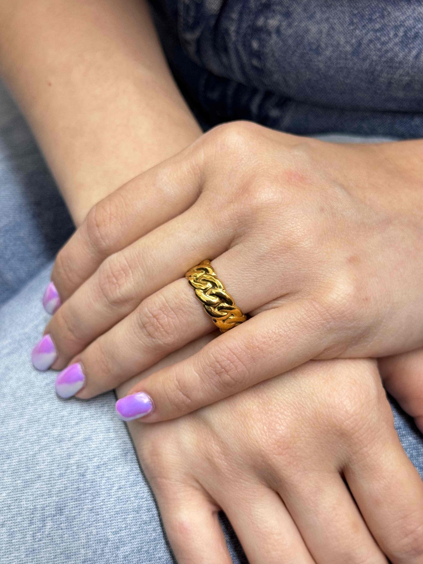 Braided gold ring on hand showcasing intricate design and elegance.