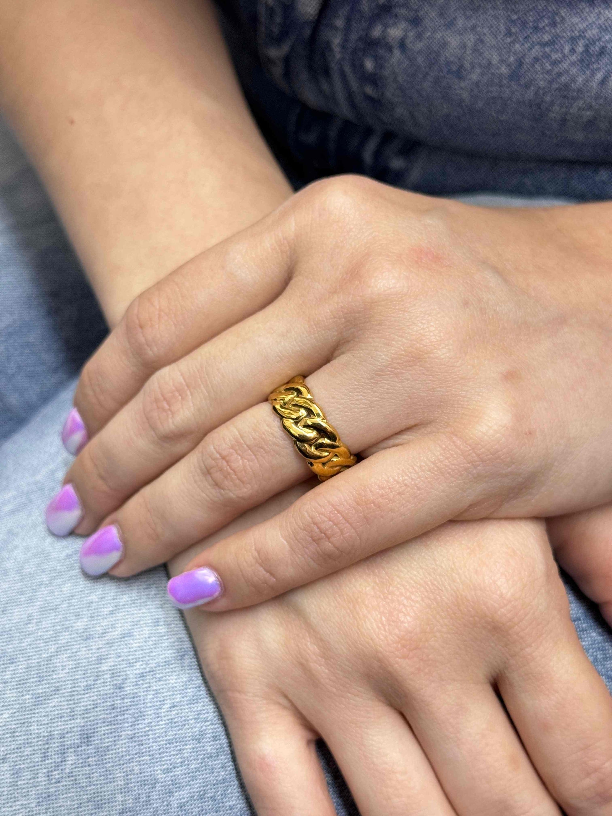Braided gold ring on hand showcasing intricate design and elegance.