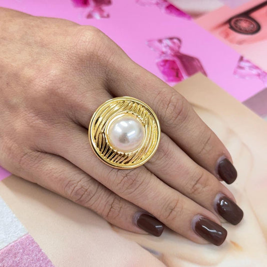 Close-up of hand wearing a BIG PEARL gold ring with a large lustrous pearl centerpiece on a pink background