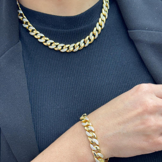 Gold chain necklace and bracelet on a person wearing a blue outfit
