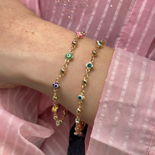 Golden bracelet with eye-shaped multi-color and white charms on wrist