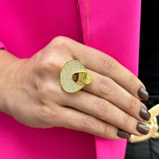 Gold adjustable modern ring with miniature crystals on hand against pink background