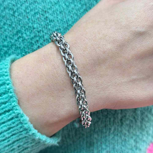 Stainless steel rolo link bracelet on wrist with turquoise sweater background