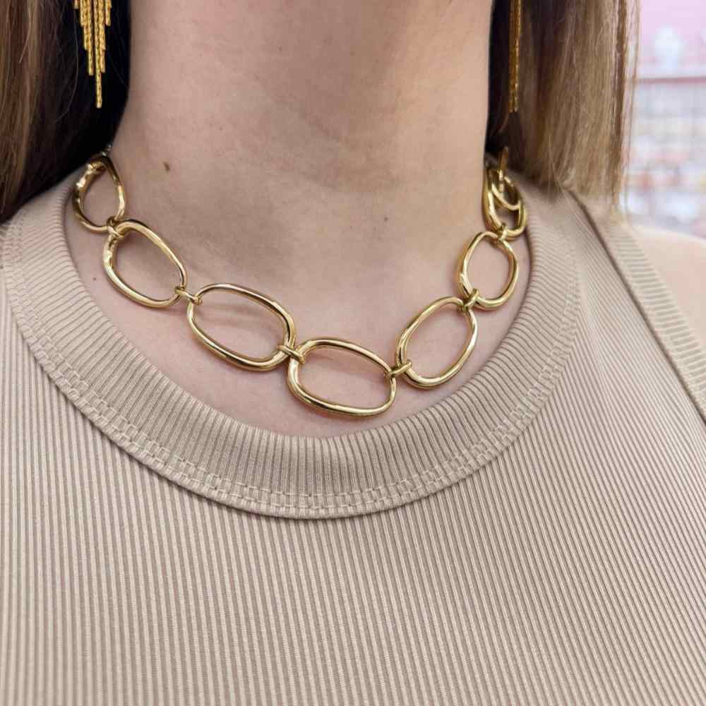 Elegant oval fashion necklace with gold link chain on woman's neck.