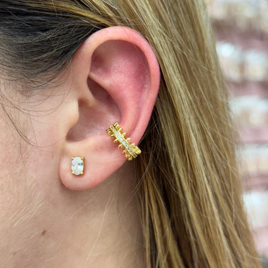 Close-up of an ear wearing gold earrings with a blurred background