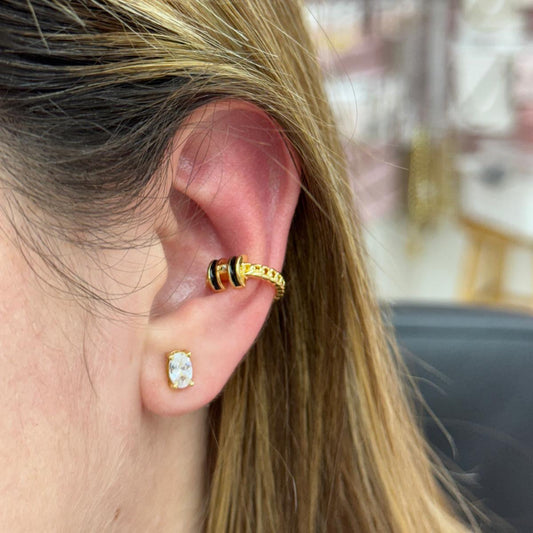 Close-up of a person wearing gold hoop earrings with a blurred background